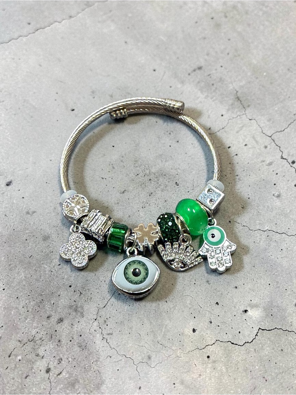 Silver Charm Adjustable Twisted Bangle with Green Eye and Hamsa Accents